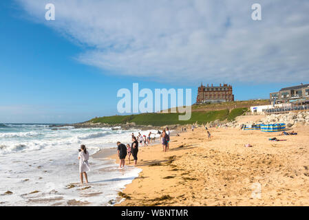 Urlauber an der Küste auf den Fistral Beach und genießen die Sonne am späten Nachmittag in Newquay in Cornwall. Stockfoto