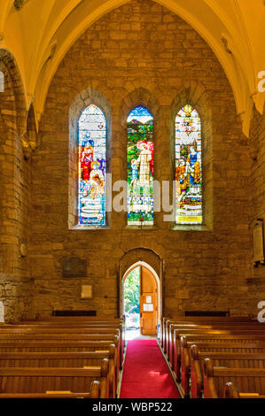 DORNOCH SUTHERLAND SCHOTTLAND KATHEDRALE VON DORNOCH INNENRAUM EINDRUCKSVOLLEN GLASFENSTER ÜBER DEM EINGANG EINGANG UND BÄNKE Stockfoto