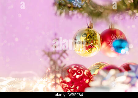 Close up Weihnachtskugeln und verschwommenes Schneeflocke hängt am Zweig der Kiefer auf rosa Hintergrund. Weihnachtsschmuck das Holiday s zu feiern. Stockfoto
