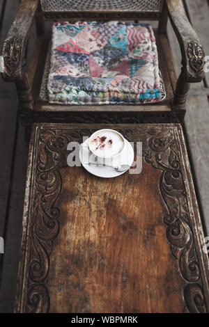 Tasse aroma Cappuccino auf vintage Holztisch, handgefertigte Schnitzerei Textur, Bali Style Stockfoto