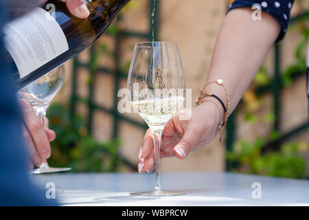 Closeup Hand gießen Weißwein von der Flasche zum Glas der Frau mit JEWERLY. Konzept Alkoholismus, Drogensucht, schlechte Angewohnheit, Sammlung sehr seltene Wein, Wein Stockfoto