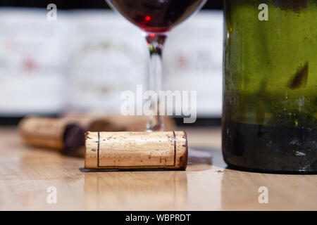 Nahaufnahme Glas Rotwein auf dem Hintergrund einer Reihe von Flaschen, Korken. Konzept Wein Burgund, Toskana, Bordeaux, professionelle Vertikale Verkostung, Pinot Noir, Stockfoto