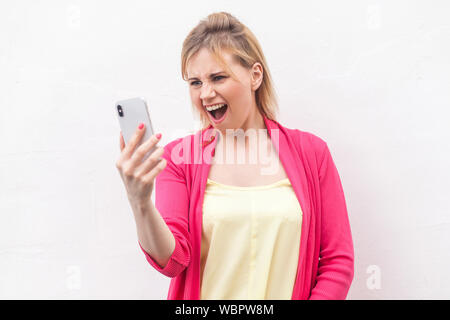 Auf keinen Fall! Portrait von Angry bossy junge Frau in rosa Bluse stehen und Beobachten auf ihr Handy mit aggressiven Gesicht. Hallenbad, isoliert, studio Shot, Stockfoto