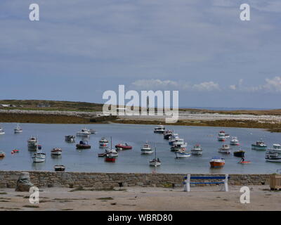 L'Île de Molène et son merveilleux Port et ses Bateaux multicolors et ses Quais de Granit et un Banc bleu et Blanc et l'île Hebeln depuis le große Stockfoto