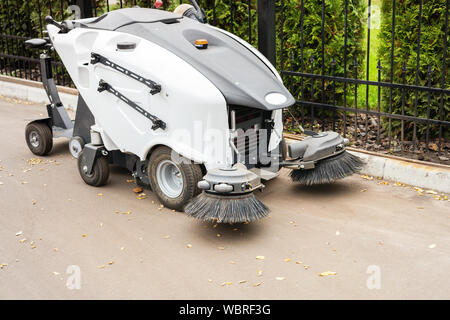 Kleine Kehrmaschine Maschine am Parkplatz Lagerung stehen nach der Reinigung City Park Alley. Fegen Staubsauger Fahrzeug entfernen Staub und Laub in Stockfoto