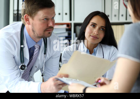 Junge Frau fragt Gruppe von GP für Heilung von Krankheit Stockfoto