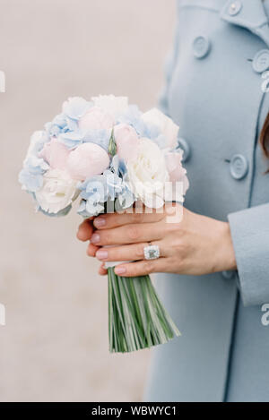 Blumenstrauß aus Knospen von Pioneer, blau hortension in den Händen eines Mädchens. Mädchen in Blue Coat hält vorsichtig eine stilvolle Ferienwohnung Strauß frischer Blumen Stockfoto