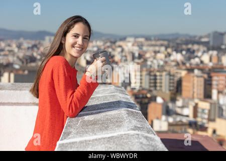 Adolescente en La Terraza tomando una taza de te sonriendo Stockfoto