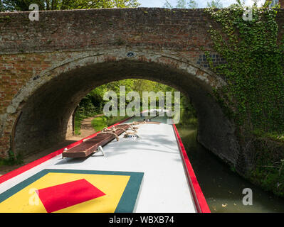 Kanal Boot unter einer Brücke auf dem Grand Union Canal, Northamptonshire, England, UK. Stockfoto