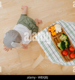 Aktiv rastloses Kind ist Essen präsentiert. Kriecht in der Nähe seiner Umgebung zu Abend essen. Stockfoto