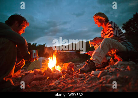 Junges Paar marshmallows Rösten über offenem Feuer beim Camping. Stockfoto