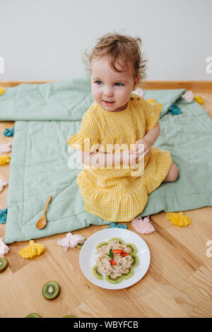 Sehr niedliches Baby essen Haferflocken mit Kiwi Stockfoto