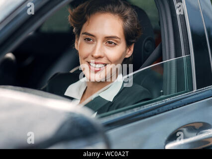 Lächelnd Geschäftsfrau in einem Auto. Junge Frauen, die in förmlichen tragen Auto fahren. Stockfoto