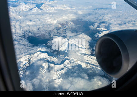 Blick aus dem Flugzeug Fenster mit Schnee bedeckten Bergen und einer der Motoren für Luftfahrzeuge. Über den Alpen, Europa. Stockfoto