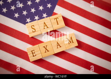 SAT Prüfung in Holzblock Buchstaben auf der US-Flagge. Stockfoto