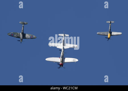Der "Historischen Fighters' Team von 4 Weltkrieg zwei Kämpfer, P-51, P-47, Spitfire und Buchon in Formation overhead Wattisham Flugplatz. Stockfoto