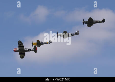 Der "Historischen Fighters' Team von 4 Weltkrieg zwei Kämpfer, P-51, P-47, Spitfire und Buchon in Formation overhead Wattisham Flugplatz. Stockfoto
