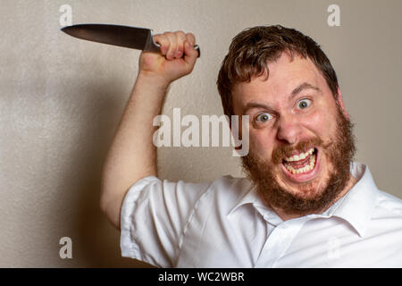 Verrückter Kerl mit einem Messer, der sich zum Angriff bereit macht Stockfoto