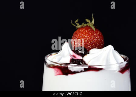 Süße nachspeise Eis in der Schüssel mit Erdbeeren Obst auf schwarzem Hintergrund. Stockfoto