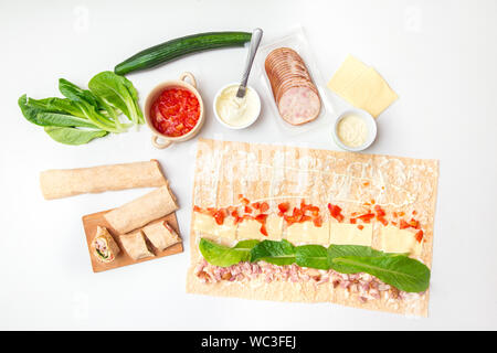 Sie rollte wrap zu Hause aus flachen lavash Brot. Verschiedene Zutaten um auf weißer Tisch. Stockfoto