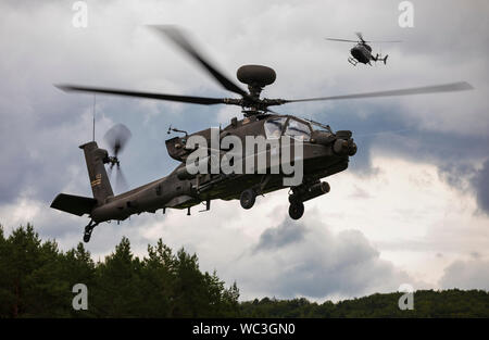 Eine AH-64 Apache Helikopter mit 1 Combat Aviation Brigade, 1 Infanterie Division, fliegen in die Box als Beobachter Controller (OC) Hubschrauber hinter, während eines simulierten Angriff Mission, als Teil der Höhepunkt Kraft auf Kraft Ausübung der kombinierten Lösung XII am Joint Multinational Readiness Center in Hohenfels, Deutschland August 19, 2019. Kombinierte Lösung ist eine halbjährliche US-Army in Europa und der siebten Armee Befehl-led-Übung bestimmt zu bewerten und zertifizieren die Bereitschaft und die Interoperabilität der US-Streitkräfte in Europa zur Unterstützung der Atlantischen Lösen mobilisiert. (U.S. Armee Foto von Stockfoto