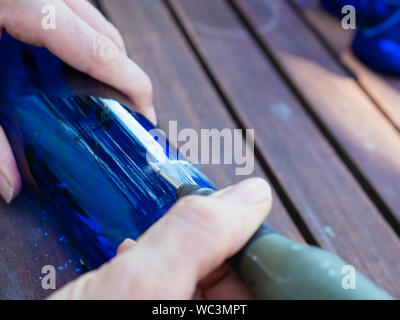 Mann Gravur eine Zahl in einer blauen Flasche es als Plot in einem Gemüsegarten zu verwenden. Stockfoto