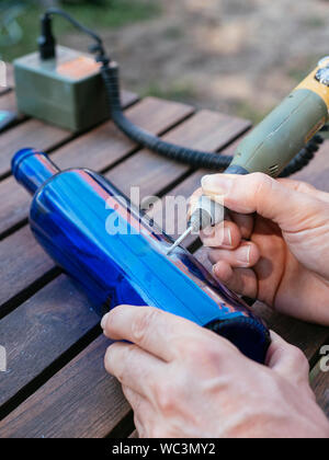 Mann Gravur eine Zahl in einer blauen Flasche es als Plot in einem Gemüsegarten zu verwenden. Stockfoto