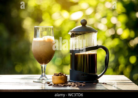 Selektiver Fokus auf Französische Presse Kaffeekanne und hausgemachte Eiskaffee, faulen Sonntag Morgen oder Abend mit kühlen Eiskaffee im Haus Garten, brechen. Werden Stockfoto