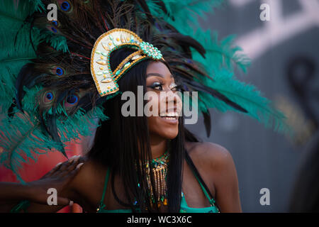 Nahaufnahme eines Performerin in pfauenfedern an der Notting Hill Carnival, London, UK, größte Karneval in Europa lächelnd gekleidet. Stockfoto