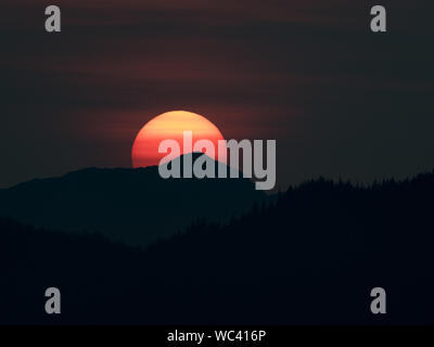 Der Sonnenuntergang über der Insel Chichagof im Südosten Alaskas, USA, machte durch Rauch aus Wildbränden lebendiger Stockfoto