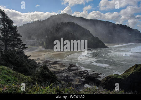 Blick von Heceta Head Leuchtturm an der Küste von Oregon, über einen Strand von Klippen isoliert, mit der Pacific Coast Scenic Byway auf einer Brücke sichtbar Stockfoto