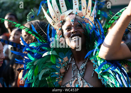 Performerin gekleidet in bunte Federn am Notting Hill Carnival, größte Karneval in Europa. Stockfoto