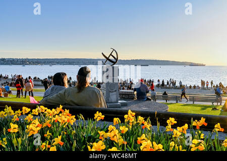 Narzissen, Sonnenuhr, Leute genießen Frühling Tag am Strand, English Bay, Vancouver, British Columbia, Kanada Stockfoto