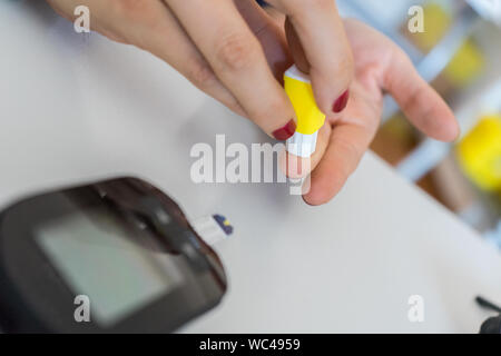 Frau Maßnahmen Diabetes mit glucometer. Schließen bis auf Hände und Finger stechen. tägliche Diabetes Control Stockfoto