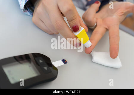 Frau Maßnahmen Diabetes mit glucometer. Schließen bis auf Hände und Finger stechen. tägliche Diabetes Control Stockfoto