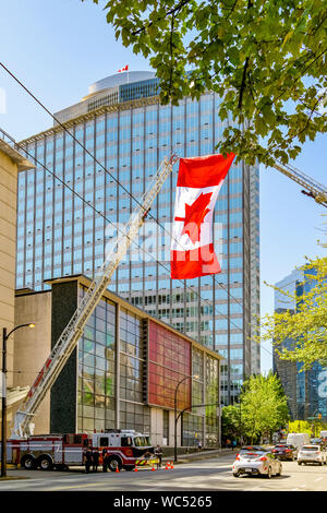 Kanadische Flagge helsd aloft durch 2 Fire Truck Leitern in Gruß zu Feuerwehrmann, die auf Aufgabe gestorben, Vancouver, British Columbia, Kanada Stockfoto