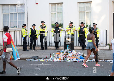 Polizisten Warten auf das Ende der Karneval mit einem Haufen Müll Säugling, Notting Hill Carnival, London Stockfoto