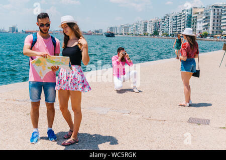 Ein paar ist das Lesen einer Karte, während die anderen Fotos ist, die ihren Sommer Urlaub. Stockfoto