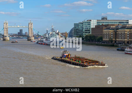 Eine große Barge im Pool von London an der Themse mit Blick auf die berühmte Tower Bridge und HMS Belfast, von London Bridge gesehen Stockfoto