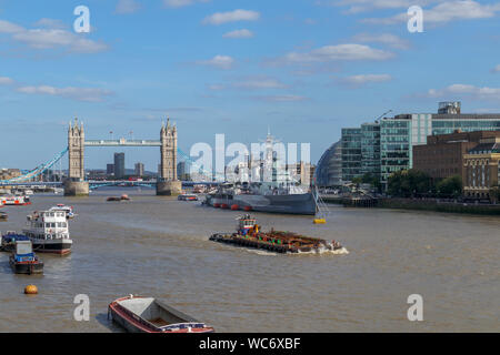 Eine große Barge im Pool von London an der Themse mit Blick auf die berühmte Tower Bridge und HMS Belfast, von London Bridge gesehen Stockfoto