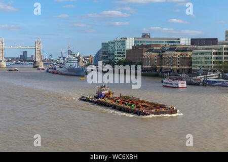 Eine große Barge im Pool von London an der Themse mit Blick auf die berühmte Tower Bridge und HMS Belfast, von London Bridge gesehen Stockfoto