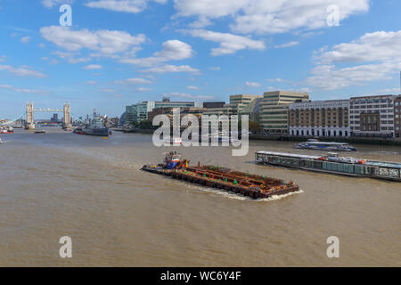 Eine große Barge im Pool von London an der Themse mit Blick auf die berühmte Tower Bridge und HMS Belfast, von London Bridge gesehen Stockfoto