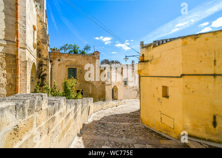 Eine steinerne Treppe führt nach unten Vergangenheit Häuser und einen hell gelb gestrichenen Wand in einem Wohngebiet der antiken Stadt Matera, Italien. Stockfoto