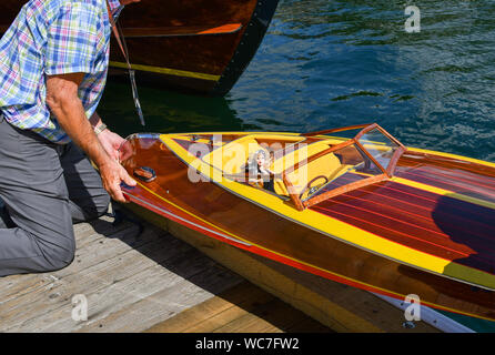 Nicht identifizierbarer Mann passt ein kleines Holzboot mit einer Barbie art Puppe in es entlang einer Dock in Coeur d'Alene, Idaho Stockfoto
