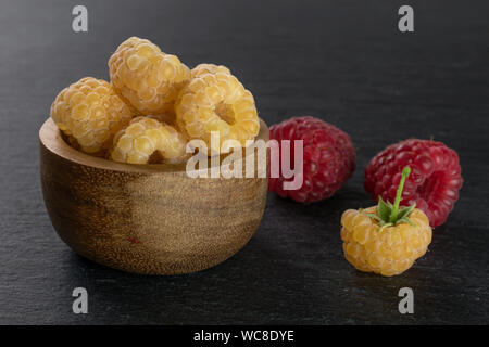 Menge ganze Frische golden hymalayan Himbeere mit zwei roten Beeren in Houten auf grauem Stein Stockfoto