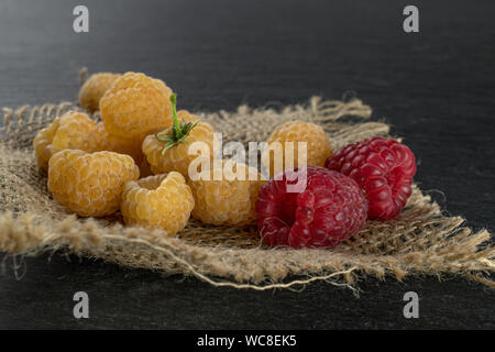 Menge ganze Frische golden hymalayan Himbeere mit zwei roten Beeren auf Jute-stoff auf grauem Stein Stockfoto