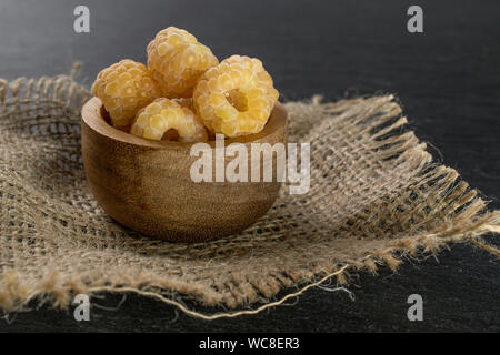 Menge ganze frische goldene Himbeere hymalayan in Houten auf Jute-stoff auf grauem Stein Stockfoto