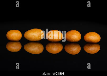 Gruppe von fünf ganze Orange gezuckerte Mutter Dragiermaschinen u.a. auf schwarzem Glas isoliert Stockfoto