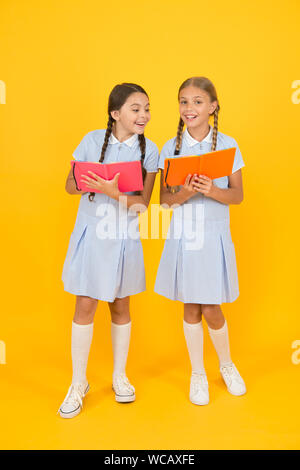 Schule Bibliothek. Pädagogische Bücher für Schulen. Bücher zu lesen. Homeschooling Konzept. Alphabetisierung Club. Süße Kinder holding Bücher auf gelben Hintergrund. Kleine Mädchen mit Lexikon oder Bücher der Kinder. Stockfoto