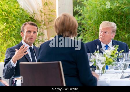 Der französische Präsident Emmanuel Längestrich, Links, Adressen, Erläuterungen der deutschen Kanzlerin Angela Merkel während des G7 Leaders' Abendessen im Biarritz Leuchtturm, als US-Präsident Donald Trump, rechts, sieht am 24. August 2019 in Biarritz, Frankreich. Stockfoto